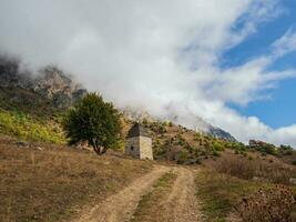 Majestic landscape with ancient tower buildings of Kelly and old family crypts in the Assinesky Gorge of mountainous Ingushetia, one of the medieval castle-type tower villages, Russia photo