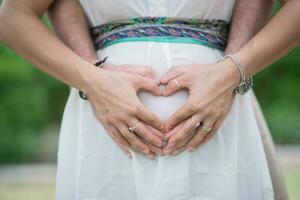 Image of parent's hands as a heart shape on belly photo