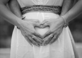 Image of parent's hands as a heart shape on belly photo