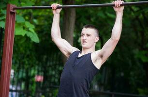 strong man doing pull-ups on a bar outdoor photo