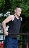 strong man doing pull-ups on a bar outdoor photo