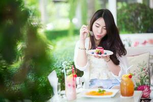 bonito niña es disfrutar con postre y bebidas foto