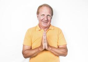 Handsome old man in orange polo-shirt doing Thai gesture or begging photo