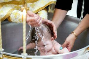 Orthodox baptism of a child. Baby in the font accepting the faith. photo