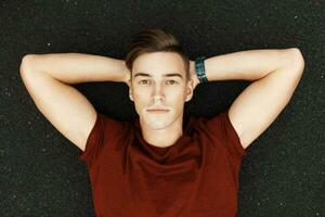 Handsome young man lying down and resting, oudtoors. Man lying on his back and looking up photo