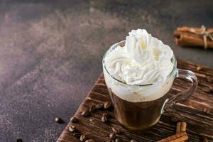 un taza de dulce viena café con azotado crema en un oscuro antecedentes foto