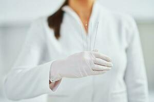 Picture of woman holding cosmetic threads in wearing gloves photo