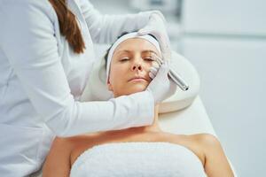 Woman having permanent eyebrows cosmetology treatment in salon photo