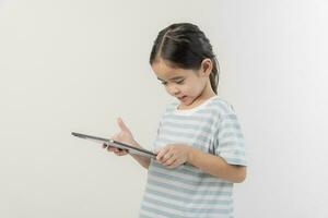 sonriente pequeño niña cosiendo y participación un tableta foto
