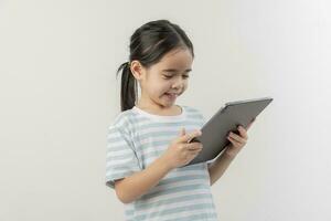 sonriente pequeño niña cosiendo y participación un tableta foto