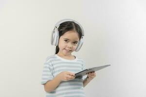 smiling little girl stiiting and holding a tablet with earphone photo