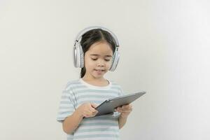 smiling little girl stiiting and holding a tablet with earphone photo