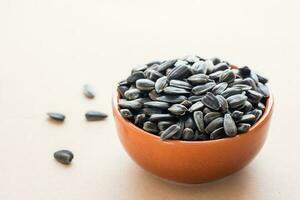 Raw unpeeled sunflower seeds in a bowl on a beige background. Natural source of vitamins and fats. Copy space photo