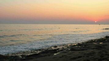 maschio piedi a piedi tra il onde Crashing su il spiaggia con colorato tramonto colori riflesso, un' giovane uomo a piedi di il mare a tramonto video