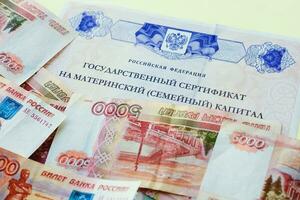 Document with Russian text State certificate of the Russian Federation for maternal capital.Russian money of five one thousand rubles. photo