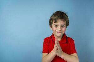 A cute 5-year-old Caucasian boy in a red T-shirt rubs hand in hand and smiles slyly. The boy is happy with the result photo