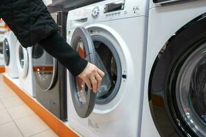 woman chooses a front-mounted washing machine in home appliance store photo