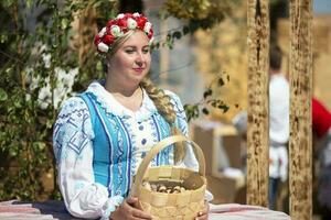 08 29 2020 bielorrusia, lyaskovichi. fiesta en el ciudad.hermosa rechoncho eslavo mujer en un bordado camisa y un guirnalda con un trenza.ruso o bielorruso étnico mujer. foto