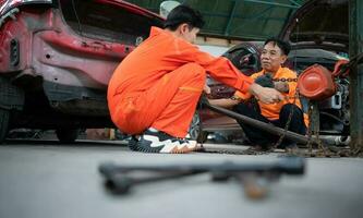 To return the automobile body to its former shape, an auto repair mechanic uses a machine to pull the car body caused by a heavy collision until it is deformed. photo