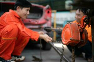 To return the automobile body to its former shape, an auto repair mechanic uses a machine to pull the car body caused by a heavy collision until it is deformed. photo