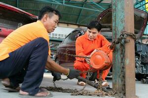 To return the automobile body to its former shape, an auto repair mechanic uses a machine to pull the car body caused by a heavy collision until it is deformed. photo