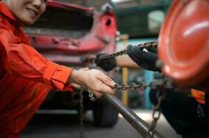 To return the automobile body to its former shape, an auto repair mechanic uses a machine to pull the car body caused by a heavy collision until it is deformed. photo