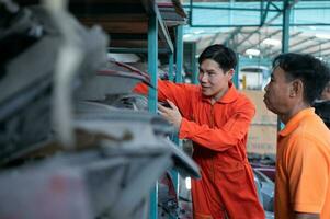 Two mechanics are selecting automobile parts, car headlights, from a spare parts warehouse in order to replace a collision's damaged headlights photo