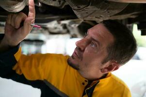 Auto repair mechanic the undercarriage of the car is being inspected for damage caused by heavy collisions. photo