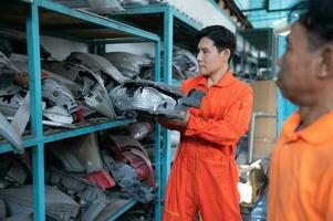 Two mechanics are selecting automobile parts, car headlights, from a spare parts warehouse in order to replace a collision's damaged headlights photo