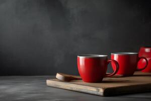 Red coffee mugs on a wooden board in front of a gray wall. photo