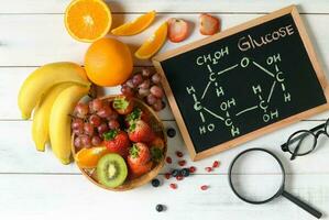 Glucose molecule on blackboard with mixed fresh fruits photo