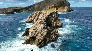 onde Crashing contro rocce su il ripido sponde di un isola video