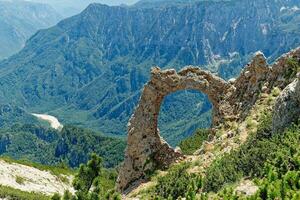View of circular rock formation in the mountains. Natural monument Hajducka vrata in Cvrsnica mountain. Famous hiking place in Bosnia and Herzegovina. photo