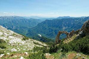 View of circular rock formation in the mountains. Natural monument Hajducka vrata in Cvrsnica mountain. Famous hiking place in Bosnia and Herzegovina. photo