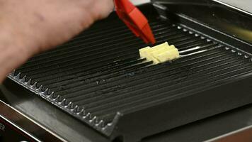 The cook greases the surface of the grill with butter, preparation for frying meat video