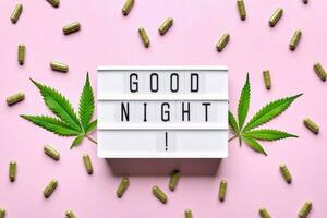 Cannabis extract capsules, hemp leaves and GOOD NIGHT letters lightbox. Calming, anti-stress and sleeping concept photo