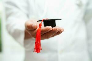 Asian woman doctor holding graduation hat in hospital, Medical education concept. photo