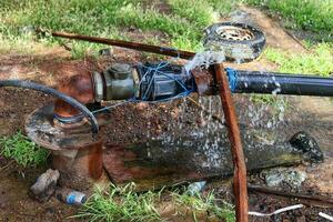 agua fuga desde el agua tubo en el jardín, fuga de defectuoso cloruro de polivinilo articulación foto