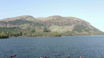 Aerial View of Canoeists in a Lake Surrounded by Mountains and Nature video