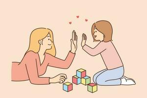 Mother and preschool daughter high-five, celebrating construction of tower of childrens blocks lying on floor. Caring mother woman raises child, involving in games that develop fine motor skills vector