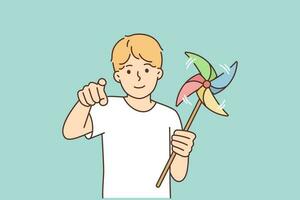 Little boy with pinwheel points finger at screen, urging you to go for walk and play together. Pre-teenage boy with multi-colored toy that spins in wind for concept of happy childhood vector