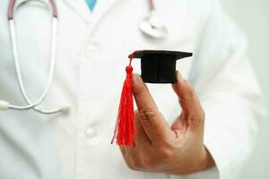 Asian woman doctor holding graduation hat in hospital, Medical education concept. photo