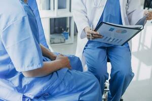 Doctor telling to patient woman the results of her medical tests. Doctor showing medical records to cancer patient in hospital ward. Senior doctor explaint the side effects of the intervention. photo