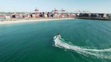 un aéreo Disparo de un Adolescente chico skurfing detrás un velocidad barco a fremantle puerto. video