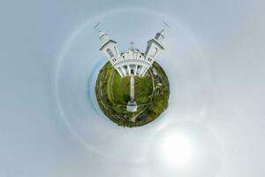 little planet transformation of spherical panorama 360 degrees overlooking church in center of globe in blue sky. Spherical abstract aerial view with curvature of space. photo