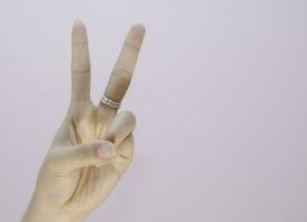 closeup woman hand showing two fingers sign language isolated on white background photo