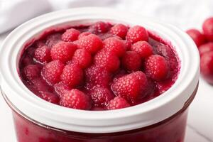 Raspberry jam in glass jars on a white background. Selective focus. photo