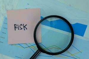 Concept of Risk write on sticky notes with diagram or graph isolated on Wooden Table. photo