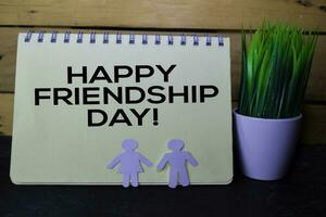 Happy Frindship Day write on Book isolated on wooden table. photo