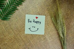 Be Happy write on sticky notes isolated on Wooden Table. photo